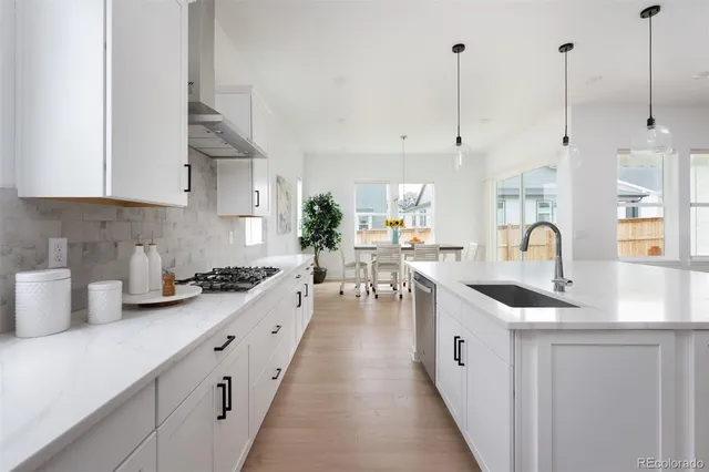 a kitchen with stainless steel appliances granite countertop a sink a stove and a wooden floors