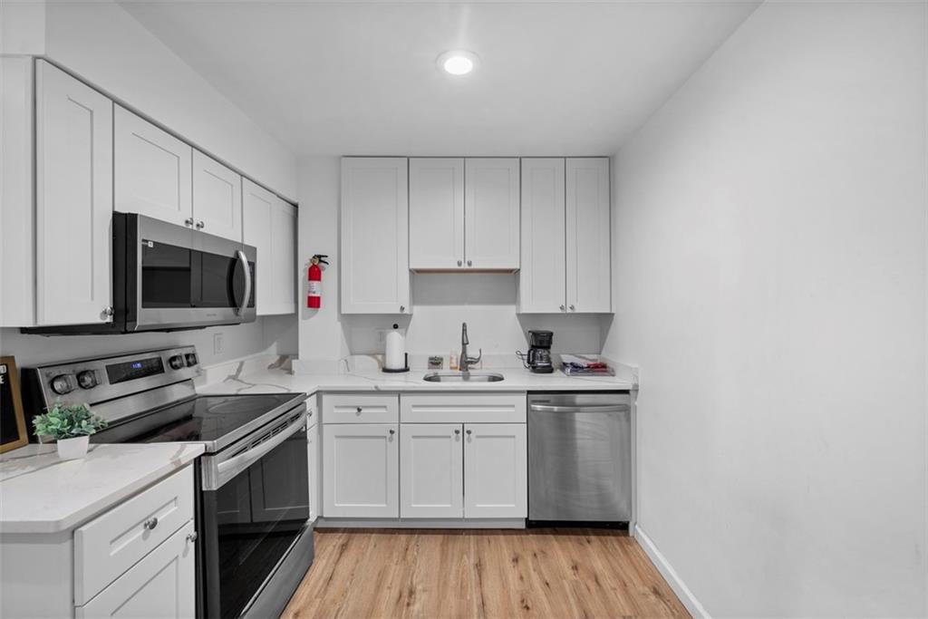 5270 Wickliff Street Pittsburgh, PA 15201 - Photo 9 of 33 a kitchen with cabinets stainless steel appliances a sink and wooden floor