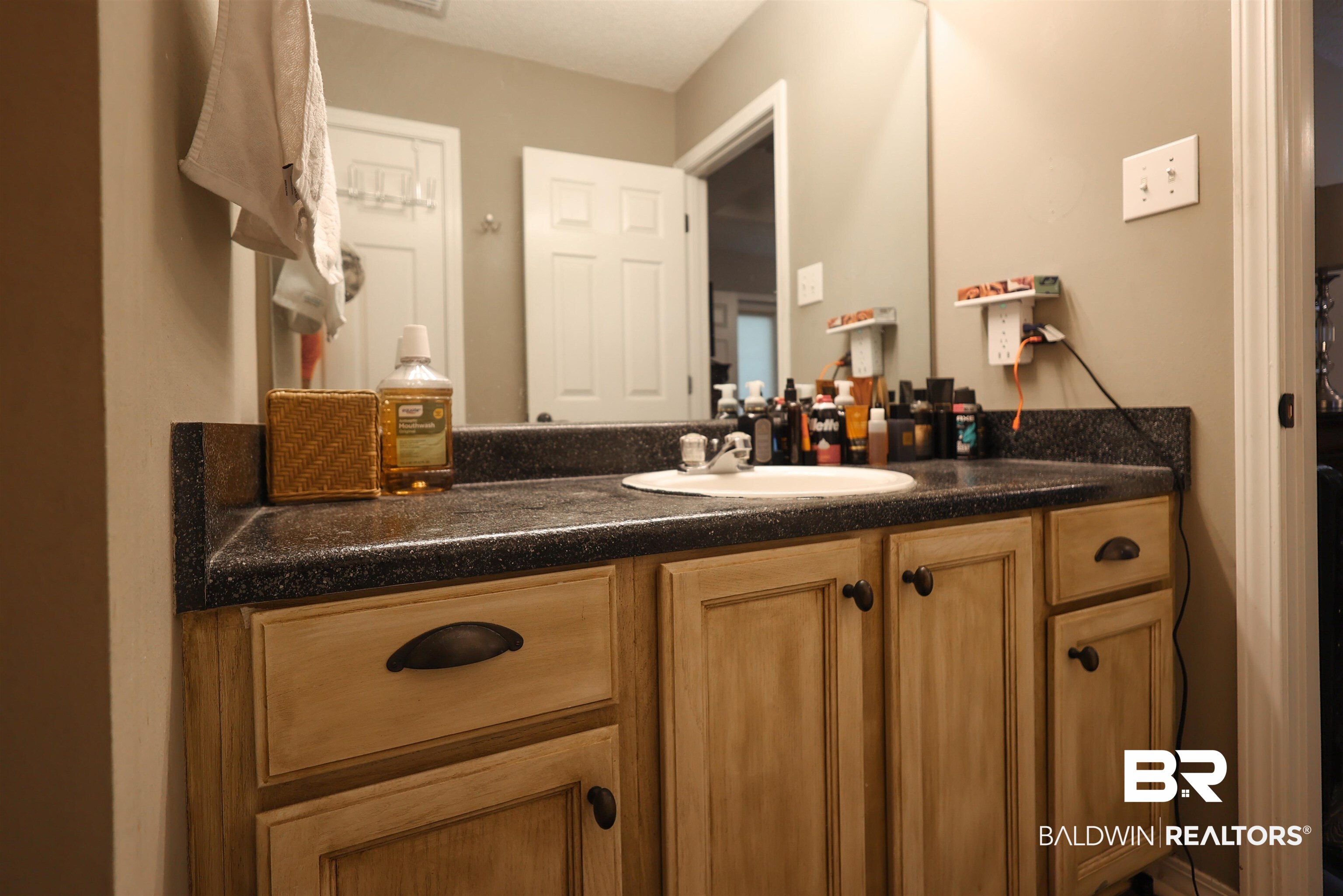 7790 Audubon Drive Foley, AL 36535 - Photo 21 of 39 Bathroom vanity featuring a speckled dark countertop and a white undermount sink with a chrome faucet