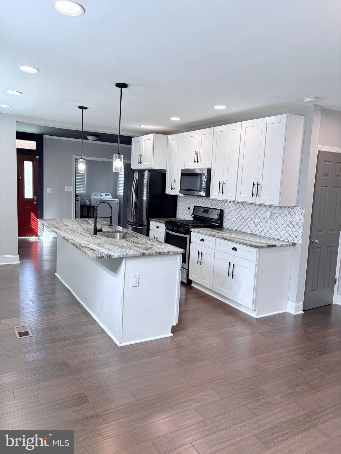 a large white kitchen with kitchen island a sink a center island stainless steel appliances and a counter space
