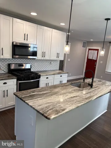 a kitchen with kitchen island granite countertop a sink a stove and a microwave