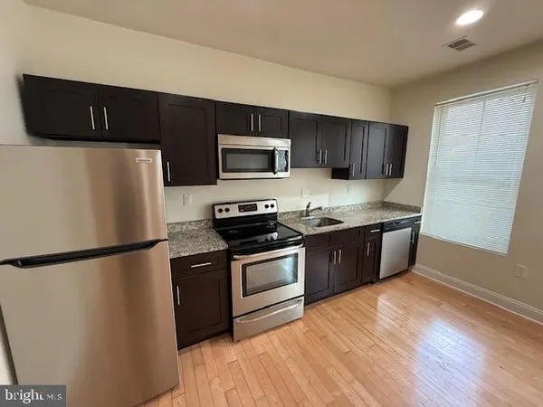 a kitchen with stainless steel appliances granite countertop a refrigerator a stove a sink dishwasher and a microwave