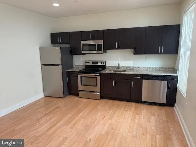 a kitchen with stainless steel appliances granite countertop a stove a sink dishwasher and a refrigerator with wooden floor