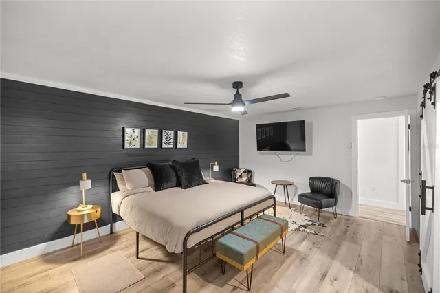 a bedroom with a bed a tv and wooden floor