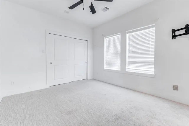 an empty room with ceiling fan and window