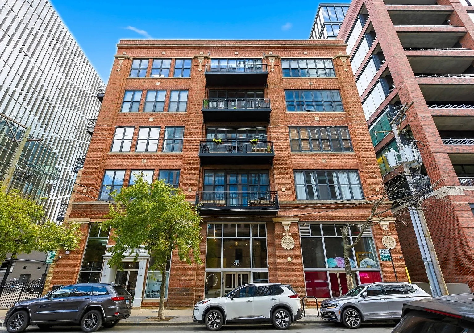 a front view of a building with lot of cars and trees