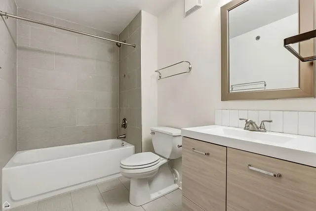 a bathroom with a toilet a sink a mirror a bathtub and vanity