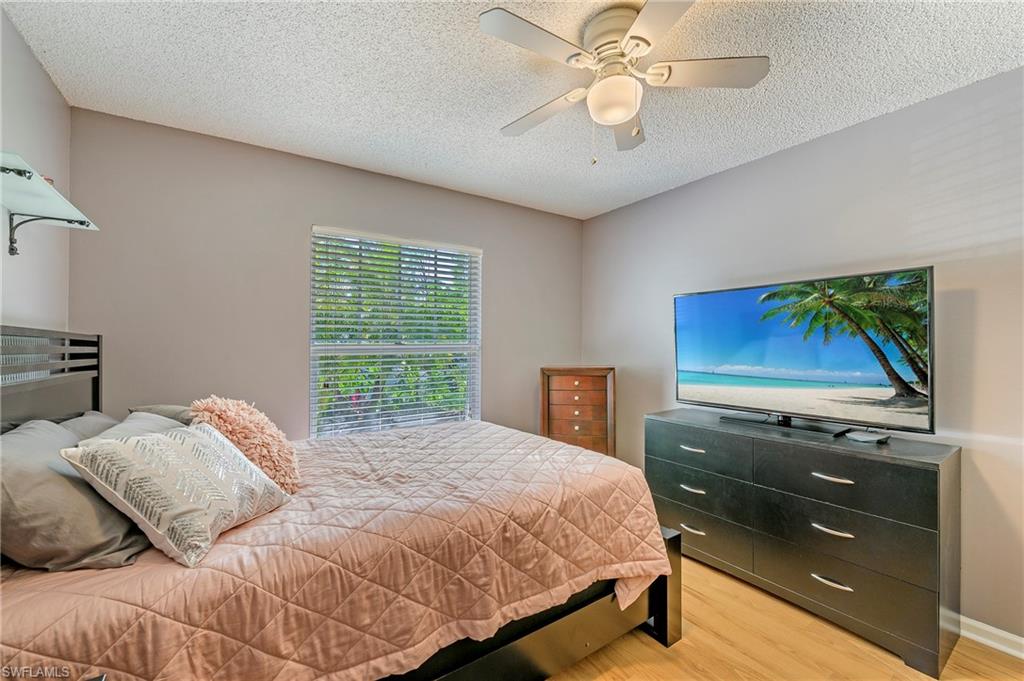 5737 Whitaker Road, Unit C103 Naples, FL 34112 - Photo 11 of 22 a bedroom with a bed and a flat screen tv