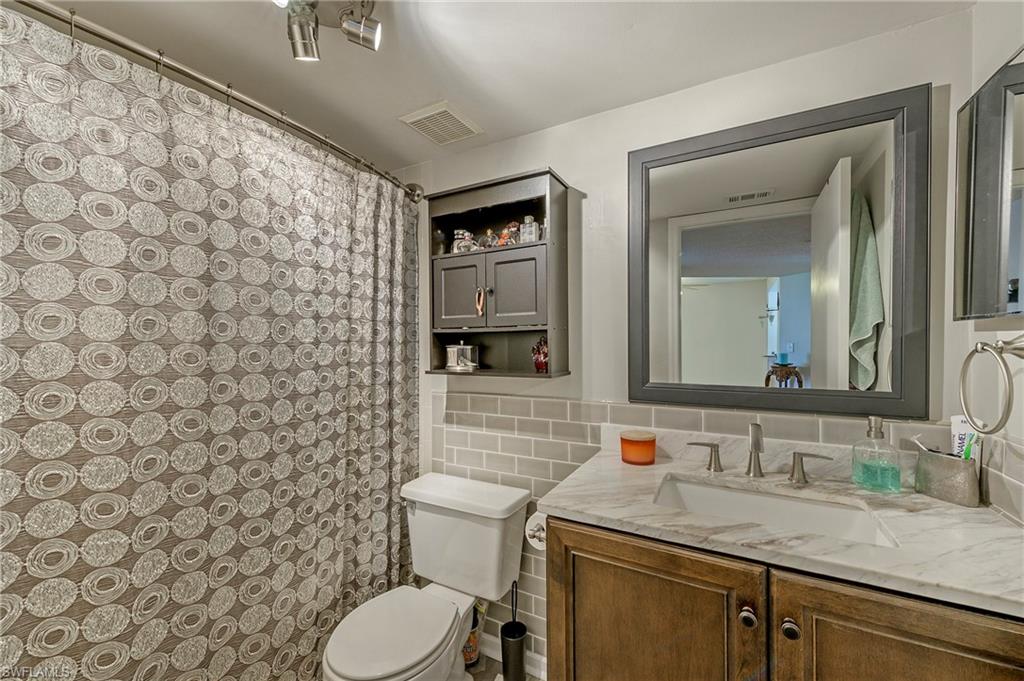 5737 Whitaker Road, Unit C103 Naples, FL 34112 - Photo 13 of 22 a bathroom with a granite countertop toilet sink and mirror