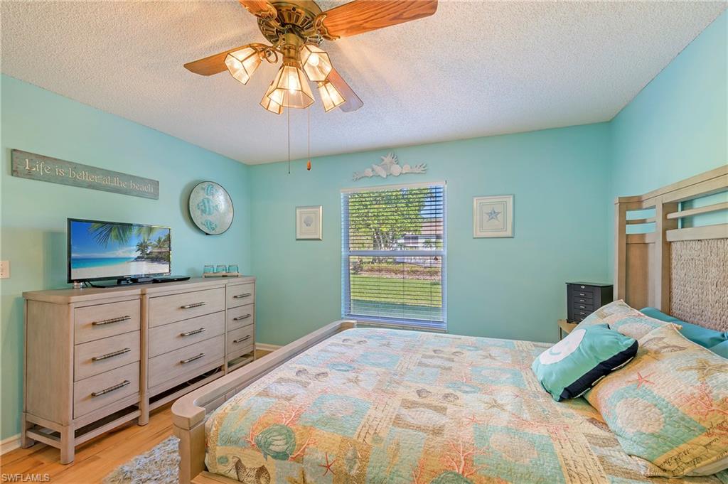 5737 Whitaker Road, Unit C103 Naples, FL 34112 - Photo 15 of 22 a bedroom with a bed and a chandelier
