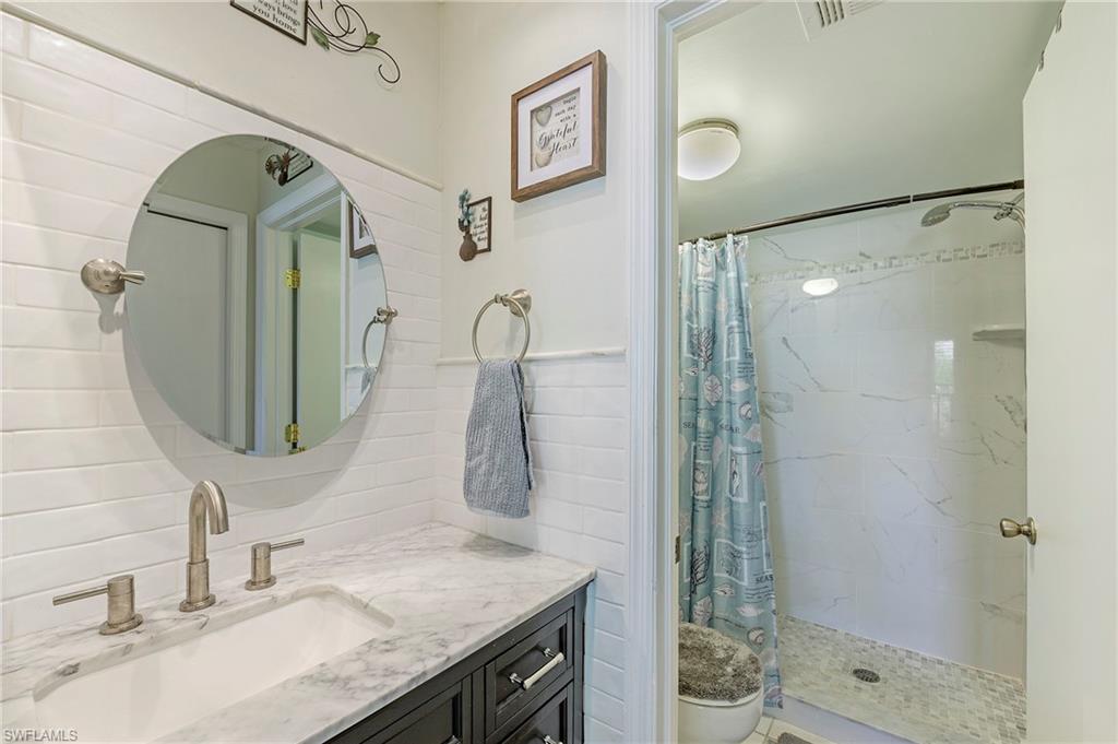 5737 Whitaker Road, Unit C103 Naples, FL 34112 - Photo 16 of 22 a bathroom with a granite countertop sink a mirror and shower