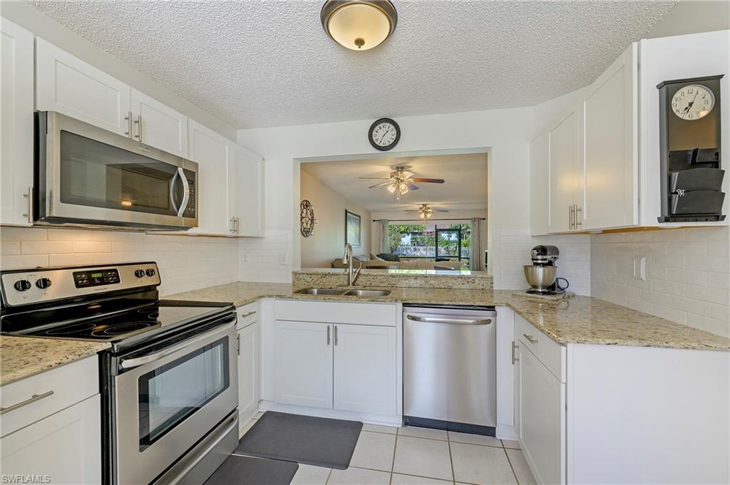5737 Whitaker Road, Unit C103 Naples, FL 34112 - Photo 8 of 22 a kitchen with stainless steel appliances a stove microwave and sink