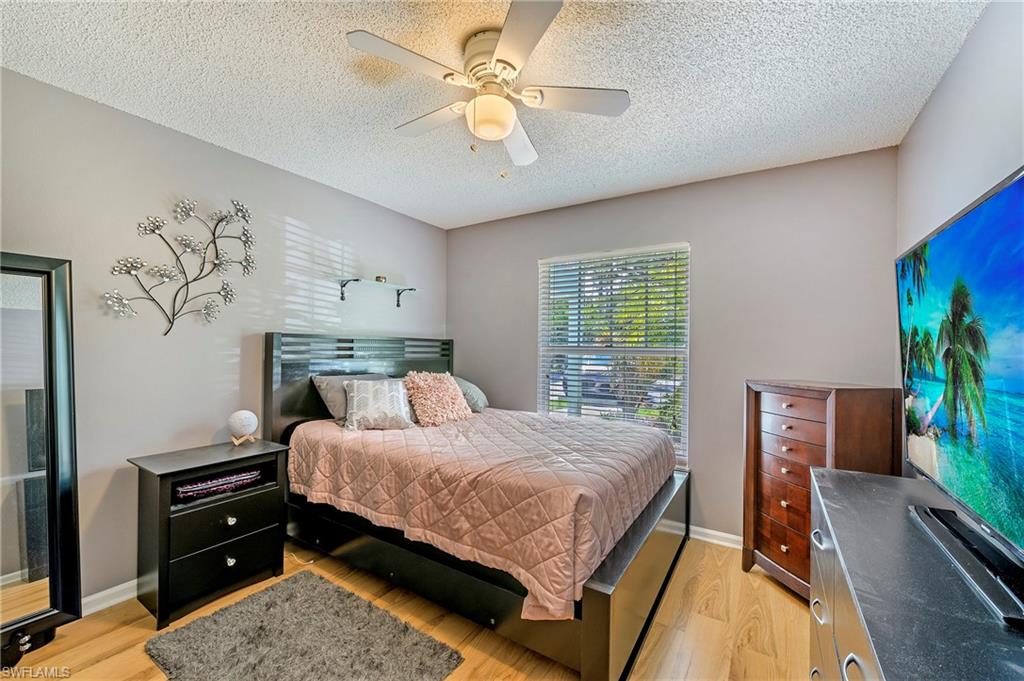 5737 Whitaker Road, Unit C103 Naples, FL 34112 - Photo 10 of 22 a bedroom with a bed and a chandelier