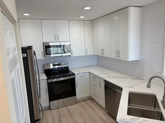 a kitchen with granite countertop a stove sink and refrigerator