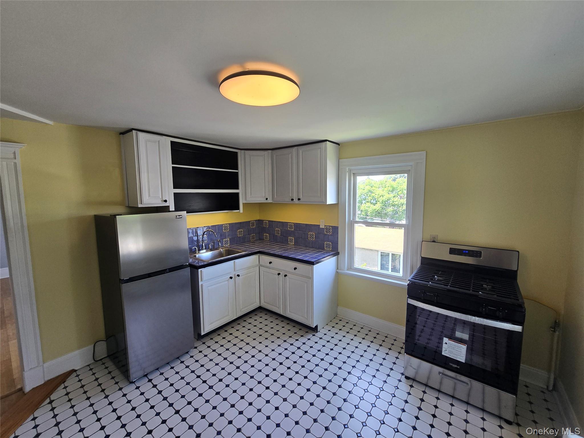 21-23 George Street Manhasset, NY 11030 - Photo 7 of 15 a kitchen with granite countertop a refrigerator and a stove top oven
