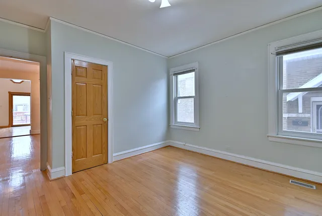 a view of empty room with wooden floor and fan