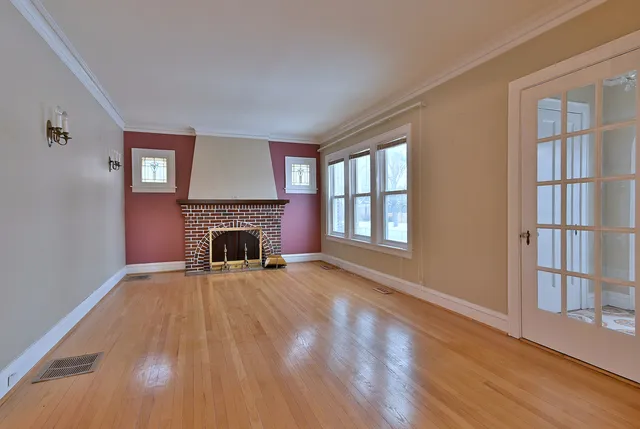 a view of an empty room with wooden floor fireplace and a window