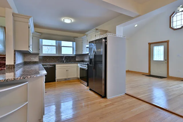 a kitchen with granite countertop a refrigerator and a stove top oven