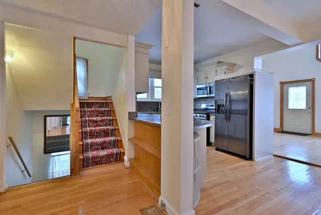 a view of a kitchen with refrigerator and wooden floor