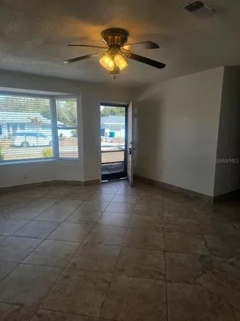 a view of an empty room and window and chandelier fan