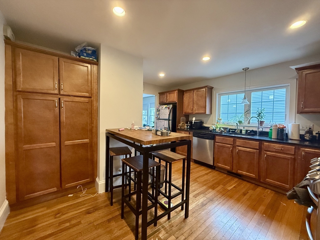 253 Brown Street, Unit 1 Waltham, MA 02453 - Photo 2 of 17 a kitchen with stainless steel appliances granite countertop a refrigerator a sink dishwasher a stove with wooden cabinets and wooden floor