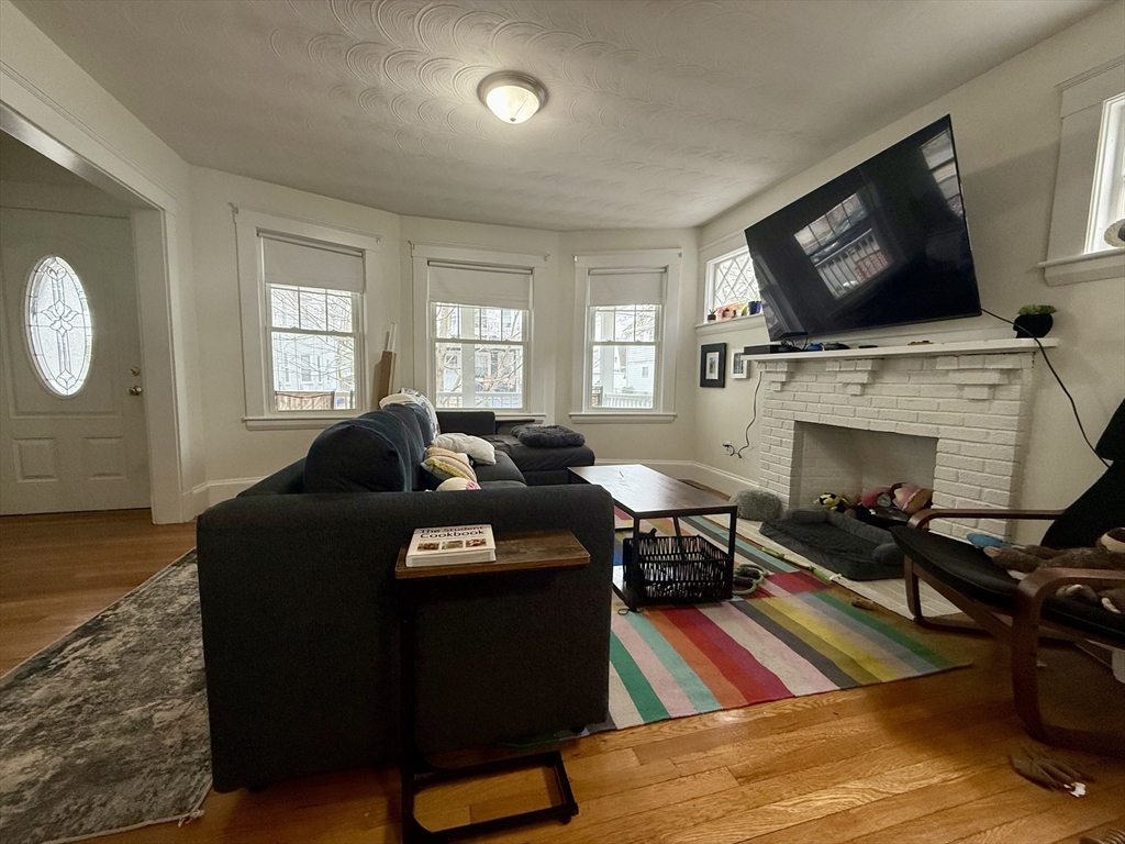 253 Brown Street, Unit 1 Waltham, MA 02453 - Photo 7 of 17 a living room with furniture a flat screen tv and a fireplace