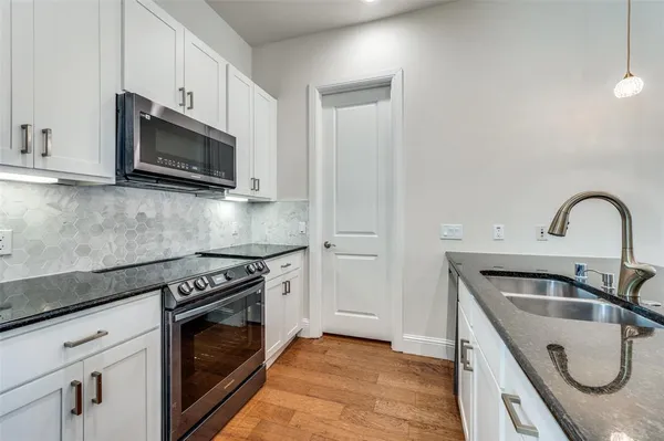 a kitchen with granite countertop a sink stainless steel appliances and cabinets