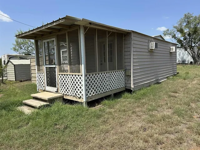 a view of a wooden house with a small yard and wooden fence