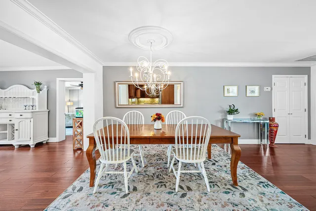 a dining room with wooden floor a chandelier a wooden table and chairs