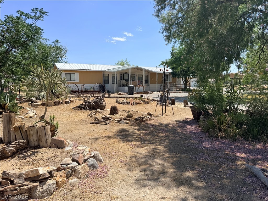 1391 West Dyer Road Pahrump, NV 89048 - Photo 4 of 50 A desert-friendly yard offers a path to a charming single-story home, accented by mature trees and local foliage.