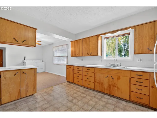 a kitchen with granite countertop wooden cabinets a sink a window and stainless steel appliances