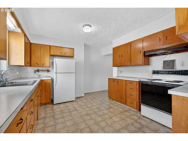 a kitchen with granite countertop a refrigerator stove and sink