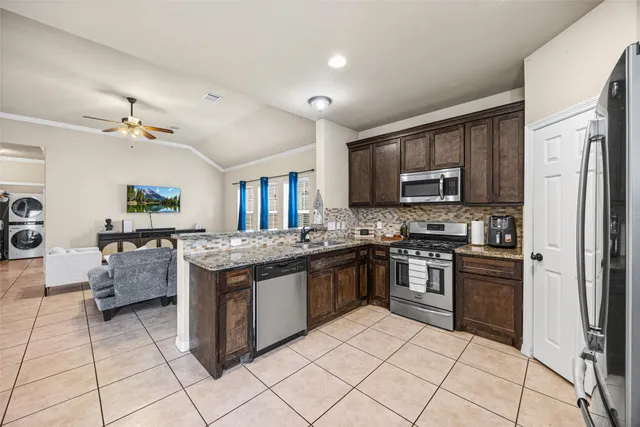 a kitchen with stainless steel appliances granite countertop a stove top oven a sink dishwasher and a refrigerator