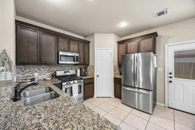 a kitchen with stainless steel appliances granite countertop a refrigerator stove and sink