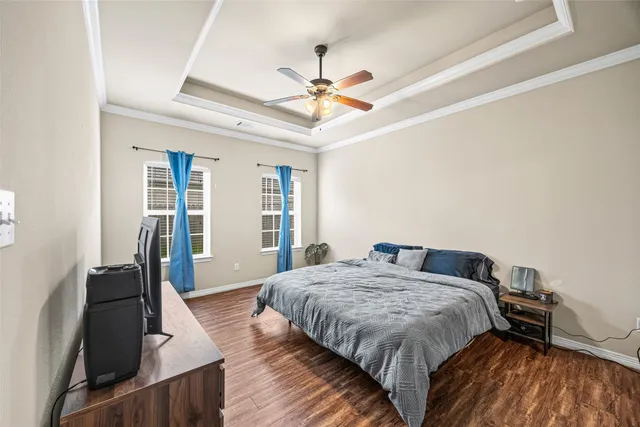 a bedroom with a bed and dresser with wooden floor