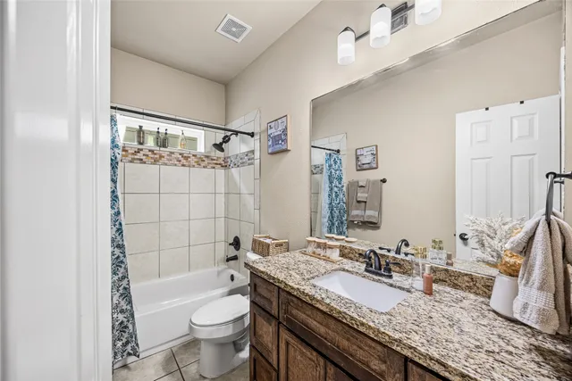 a bathroom with a granite countertop sink mirror vanity and toilet