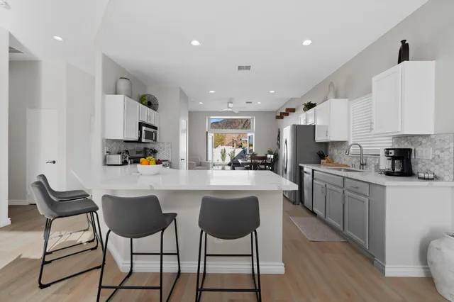 a kitchen with white cabinets and chairs