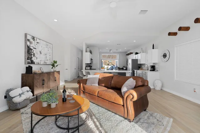 a living room with furniture and a dining table with wooden floor