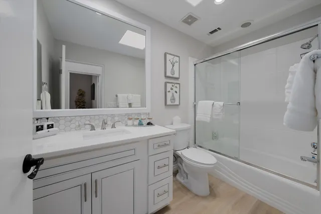 a bathroom with a double vanity sink toilet mirror and shower