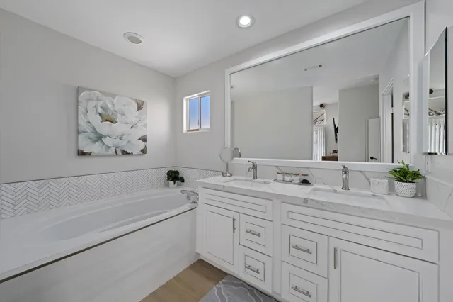 a bathroom with a double vanity sink mirror and bathtub