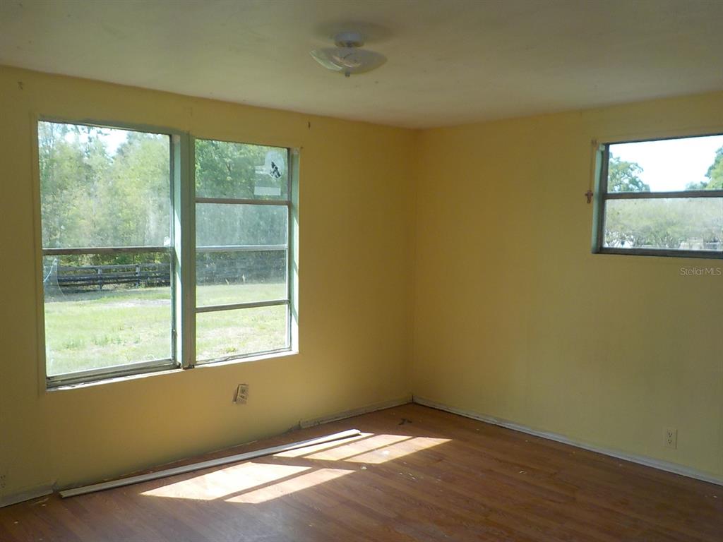7445 Southwest 15th Place Ocala, FL 34474 - Photo 22 of 27 a view of an empty room with wooden floor and a window