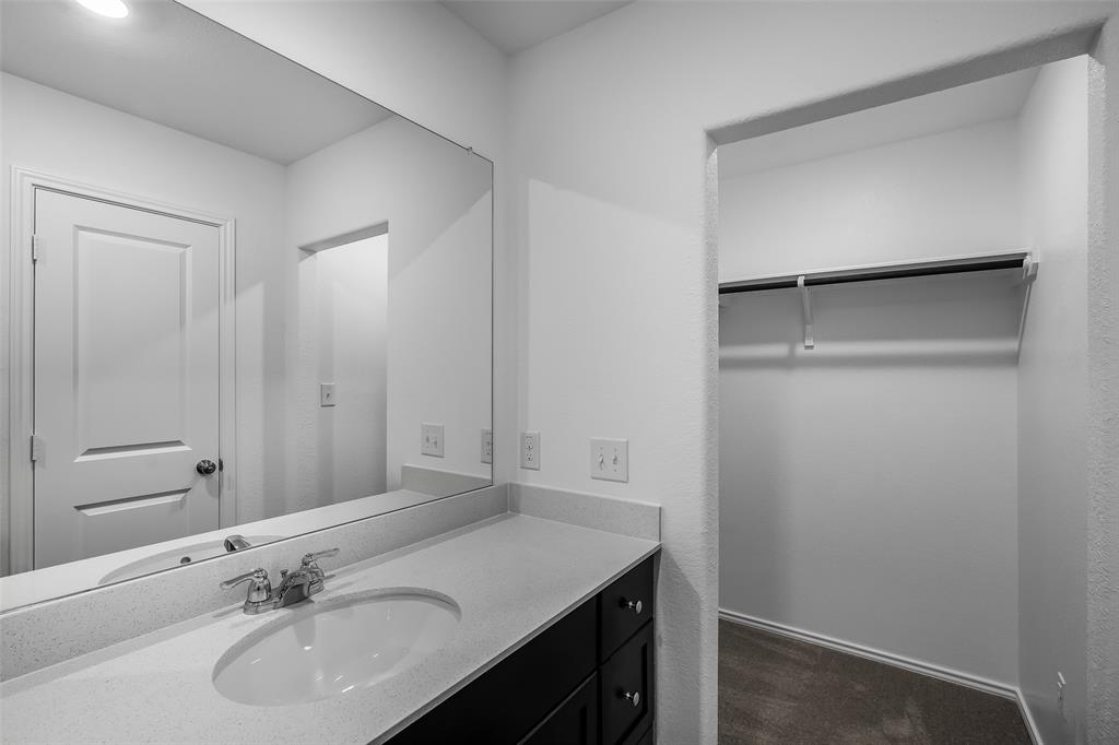 61 Trinity Circle Lockhart, TX 78644 - Photo 8 of 14 Bathroom vanity featuring an integrated sink, polished chrome faucet, and expansive wall-mounted mirror