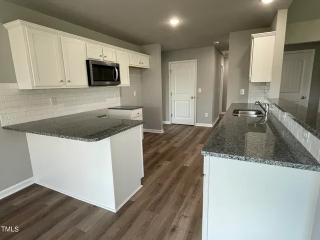 a kitchen with granite countertop a sink and a stove top oven