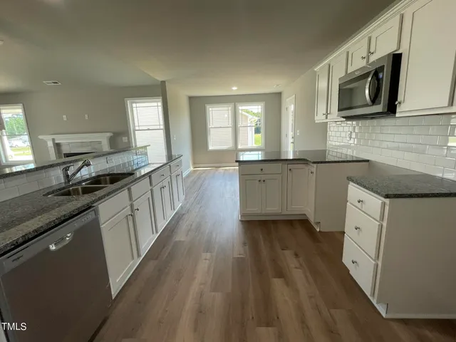 a large kitchen with cabinets stove top oven and sink
