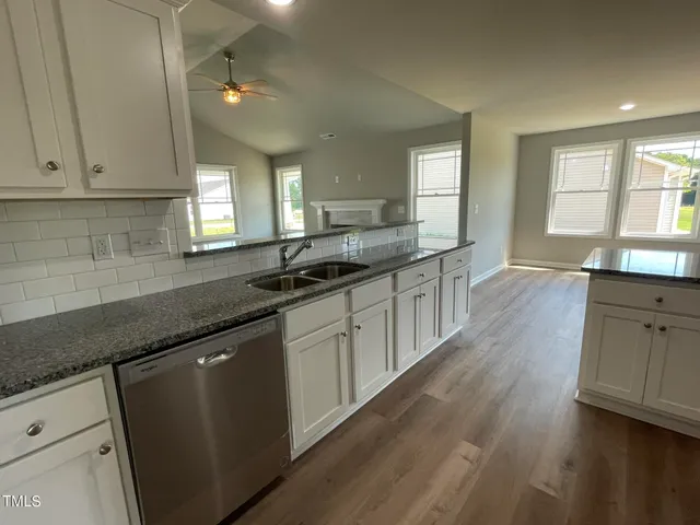 a kitchen with granite countertop a sink a stove cabinets and wooden floor