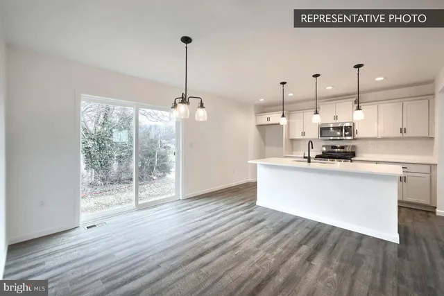 a kitchen with stainless steel appliances granite countertop a refrigerator a oven a white counter space and wooden floor