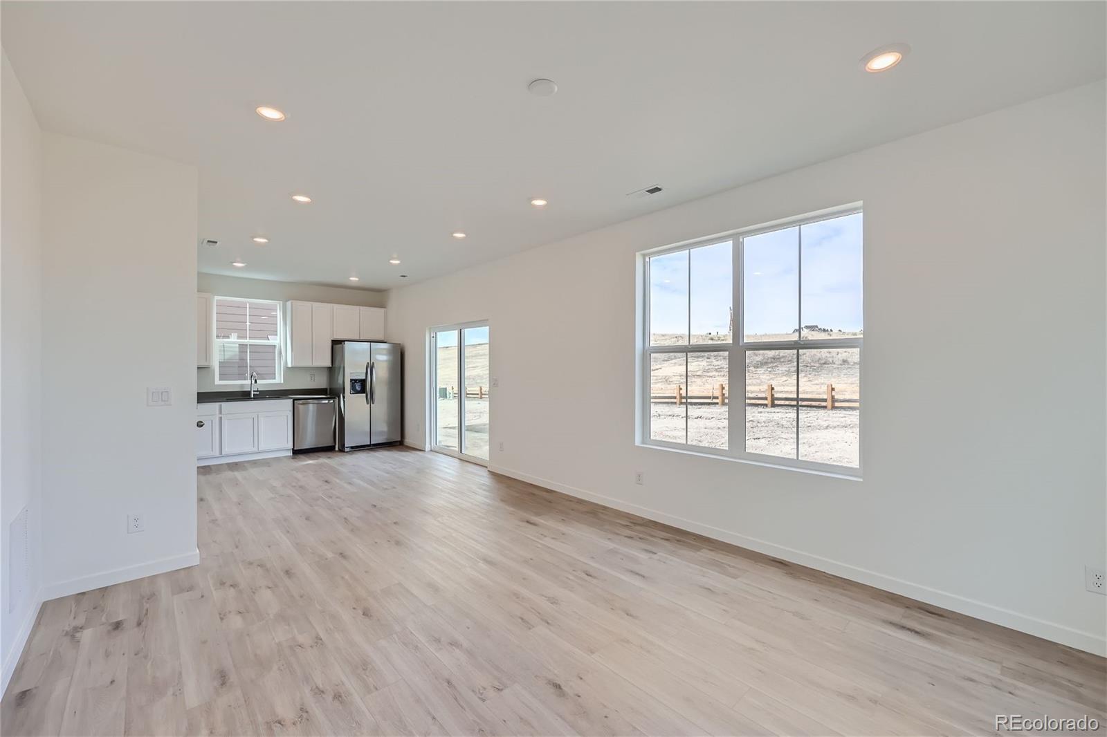864 Yankee Boy Loop Elizabeth, CO 80107 - Photo 5 of 36 an empty room with wooden floor and windows