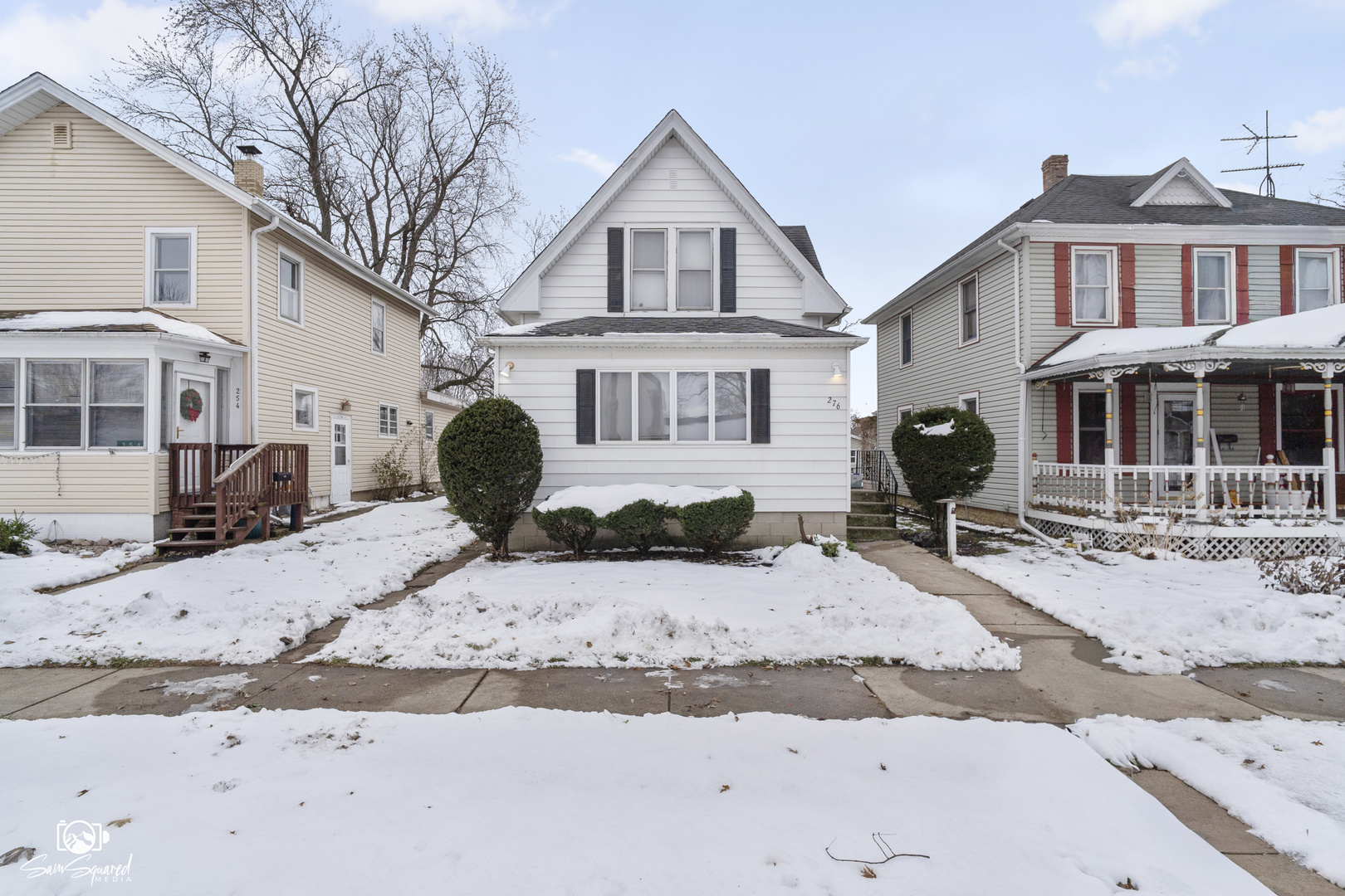 a front view of a house with a yard covered in snow