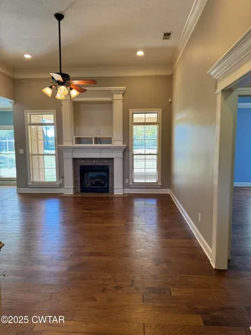 a view of an empty room with wooden floor fireplace and a window