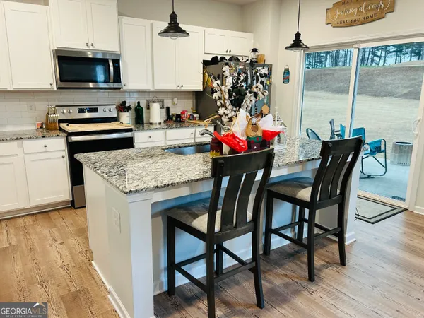 a kitchen with stainless steel appliances granite countertop a stove top oven a sink a dining table and chairs with wooden floor